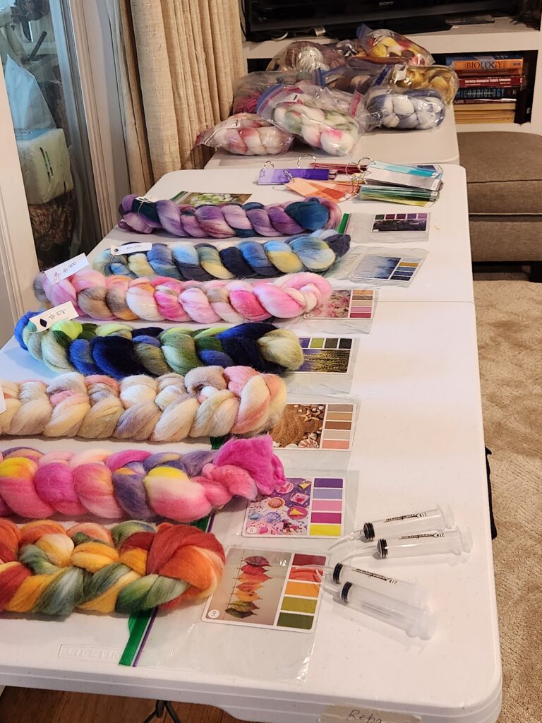 A variety of wool/silk braids on a table, with color cards
