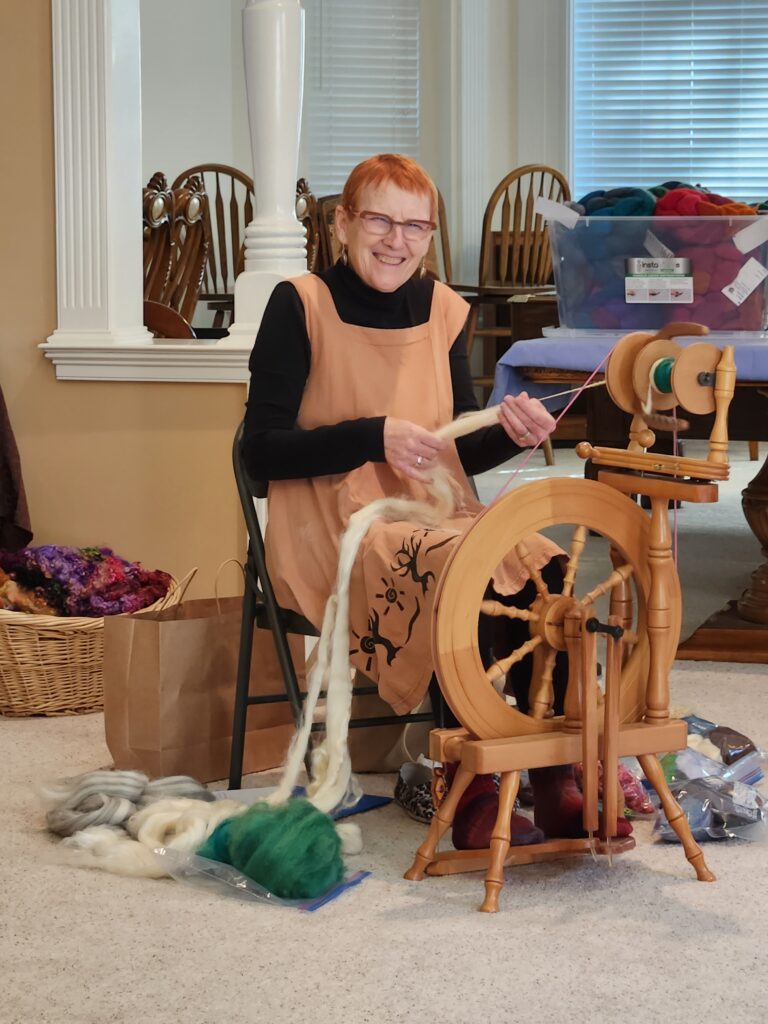 Smiling spinner at her spinning wheel