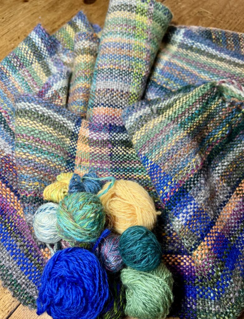 multi-color woven scarf with balls of yarn